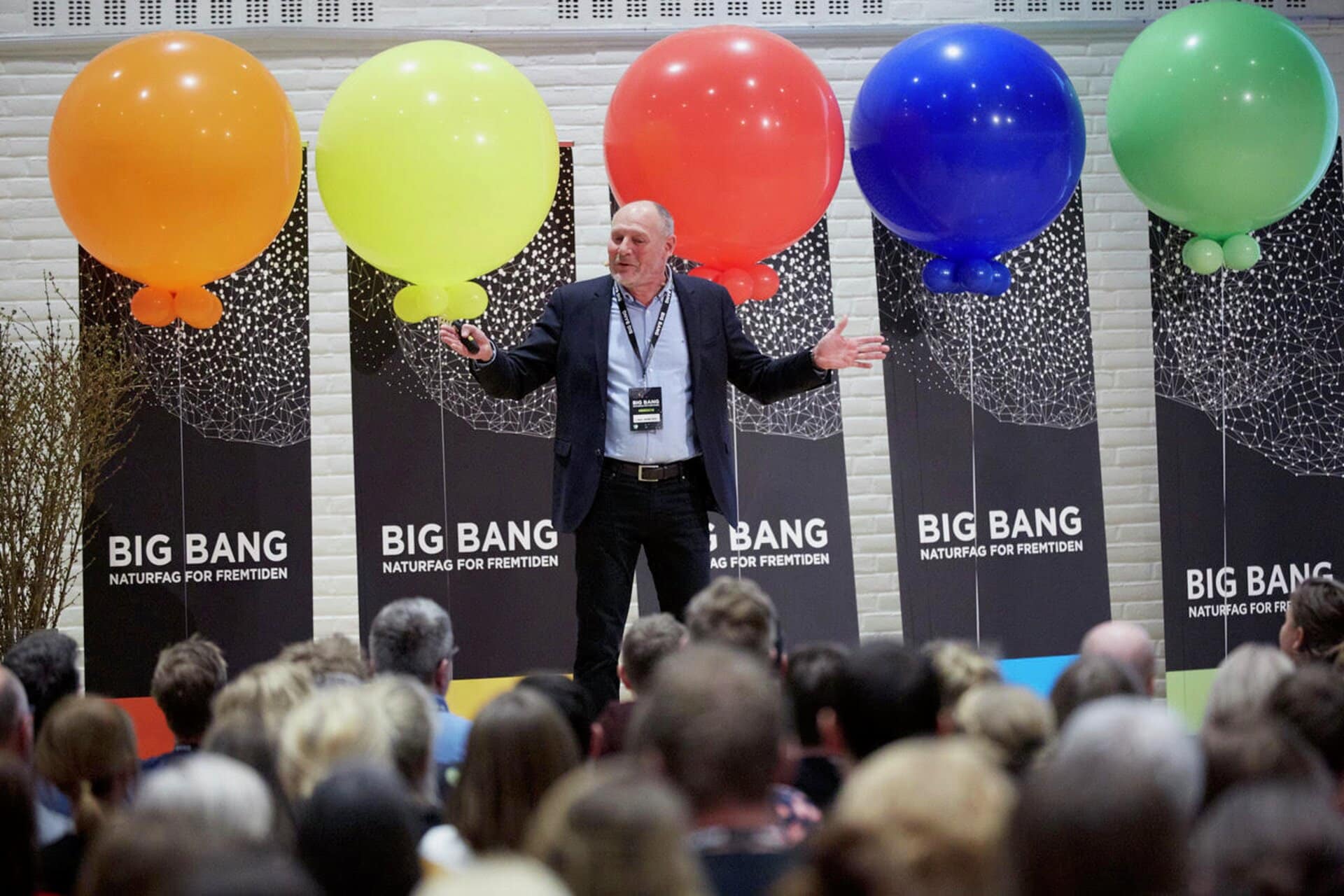 Keynote speaker med balloner og Big Bang-roll ups i baggrunden